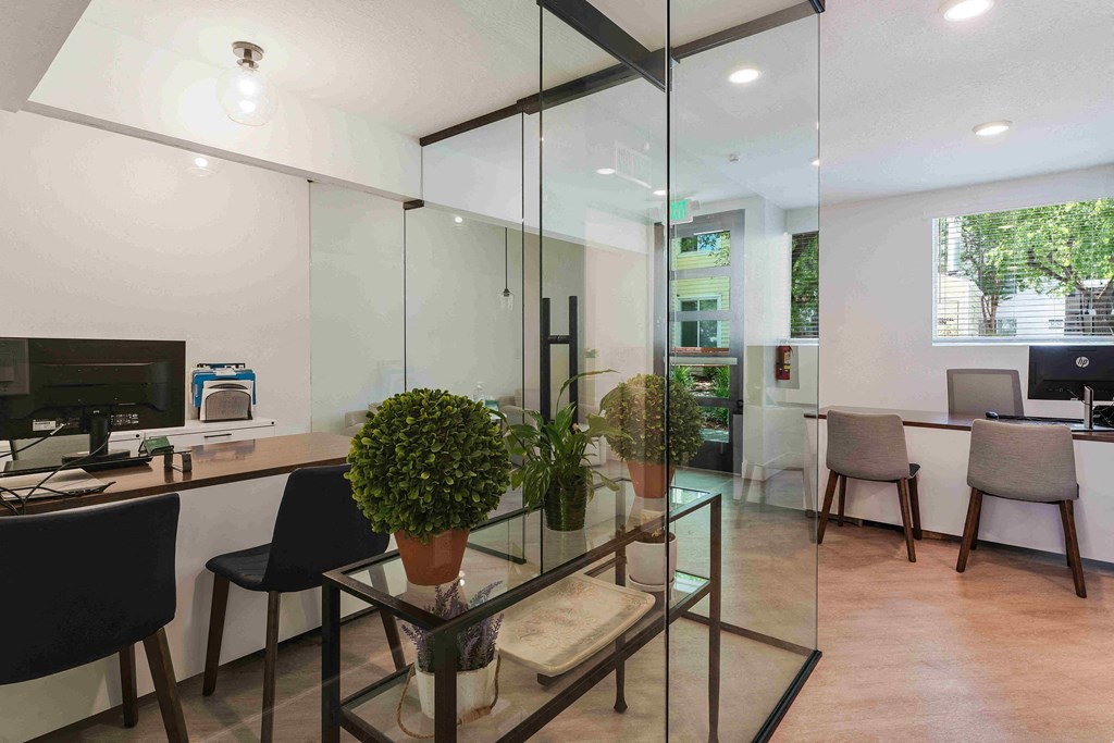 an office with glass walls and a desk with a computer