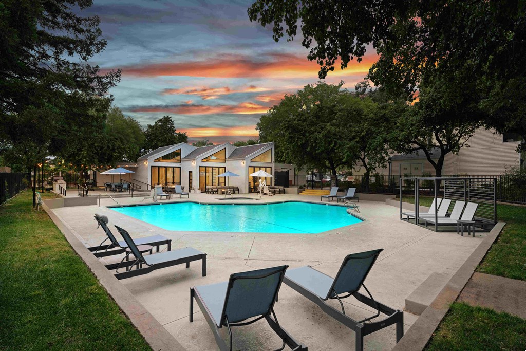 a swimming pool with chaise lounge chairs and a house in the background
