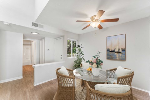 a dining room with a glass table and rattan chairs