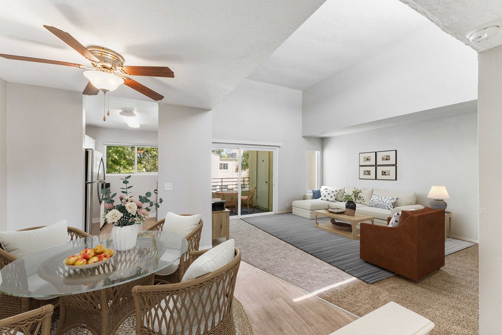 a living room and dining room with white walls and a ceiling fan