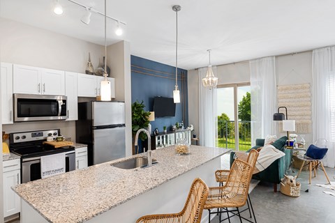 an open kitchen and living room with a granite counter top