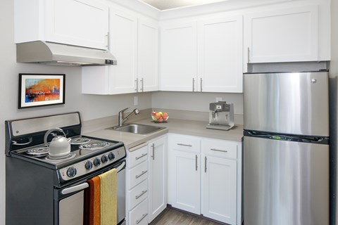 A kitchen with white cabinets and a stainless steel refrigerator.