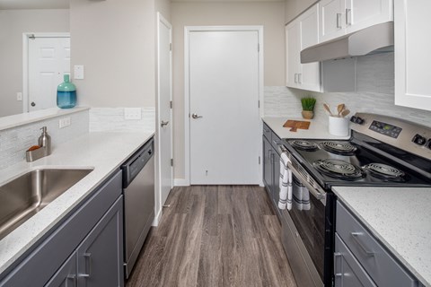 A kitchen with a white door and a stove top oven.