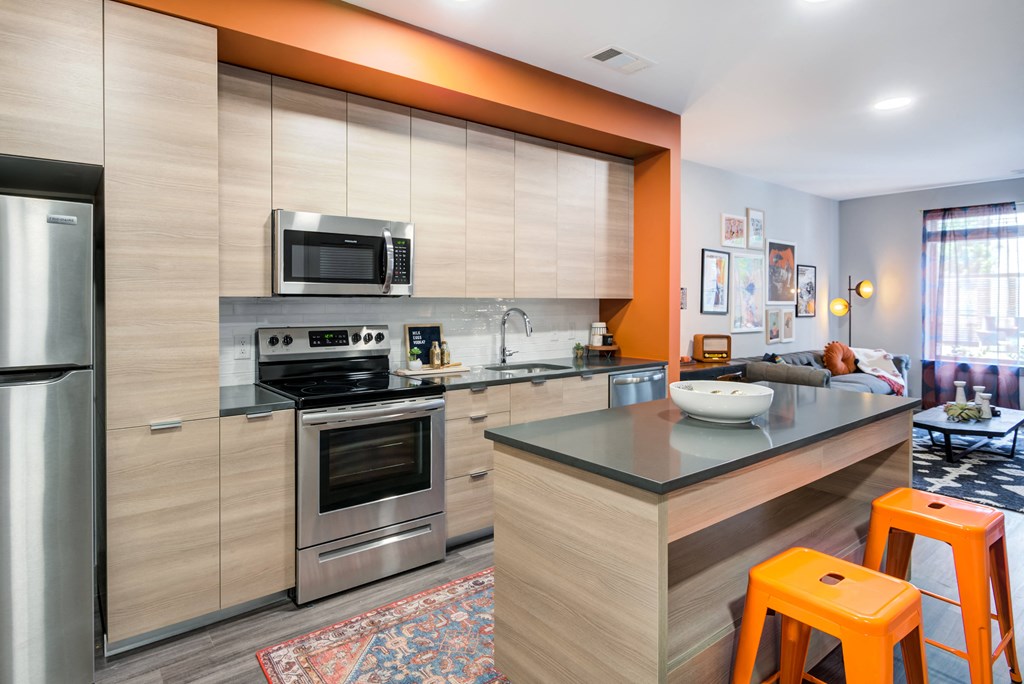 a kitchen with stainless steel appliances and a counter with orange stools