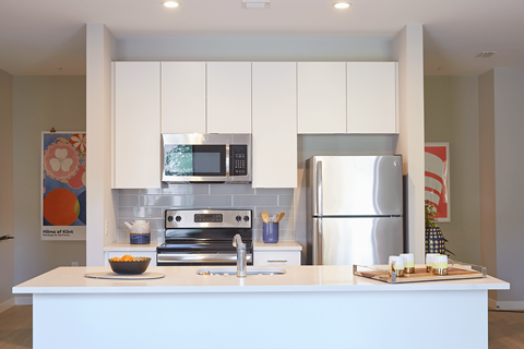 A modern kitchen with white cabinets and stainless steel appliances.