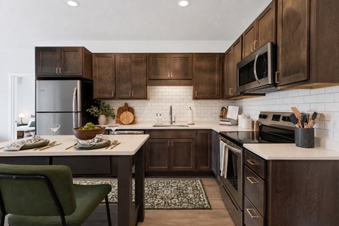 A modern kitchen with dark wood cabinets and a green chair.