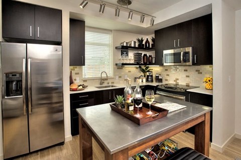 A modern kitchen with a stainless steel refrigerator and a wooden island.