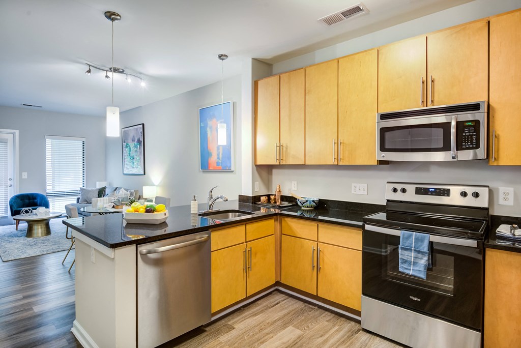 an apartment kitchen with stainless steel appliances and wooden cabinets