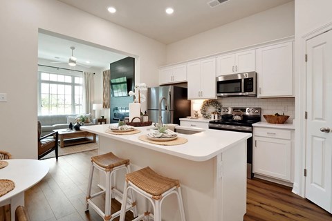 A kitchen with white cabinets and a large island with bar stools.