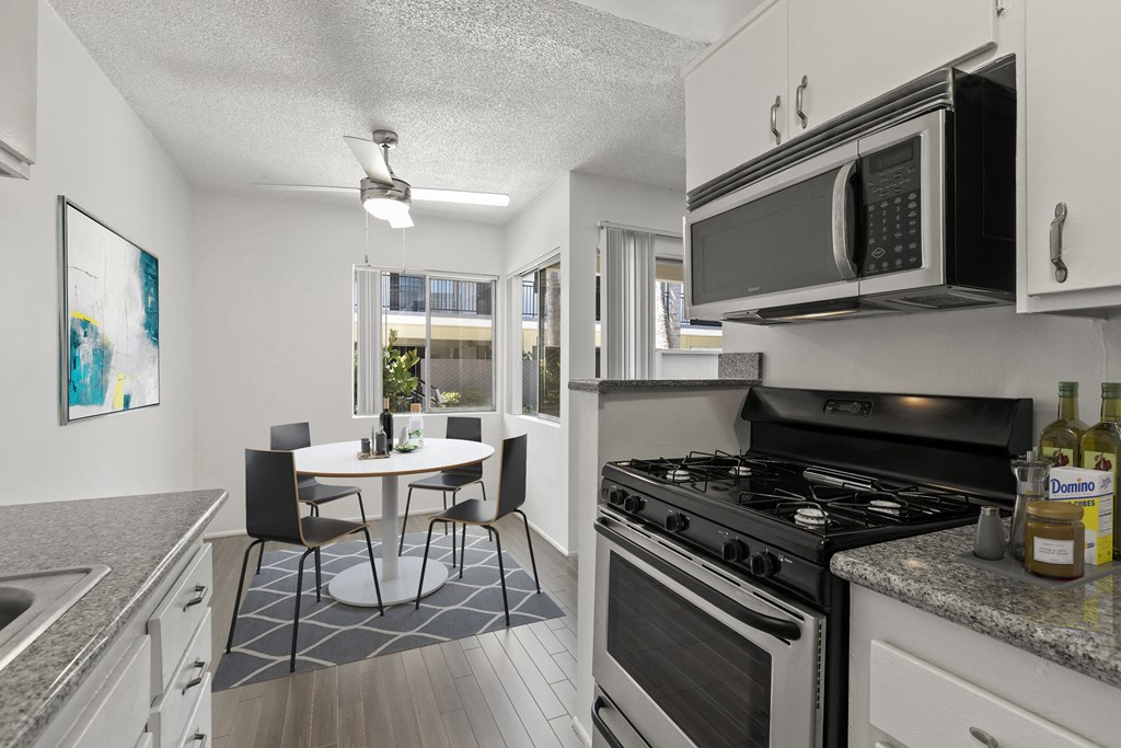 a kitchen and dining room with a stove and microwave and a table and chairs at Pacific Rose, Los Angeles, CA
