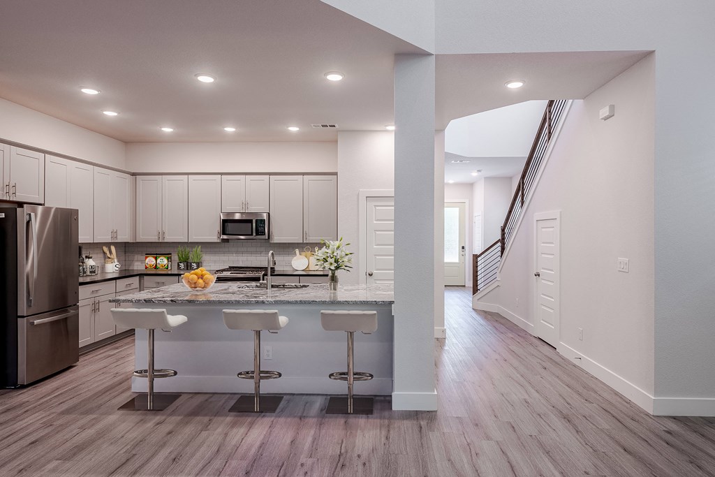 an open kitchen with a large island with three bar stools