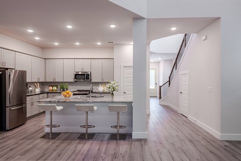 an open kitchen with a large island with three bar stools