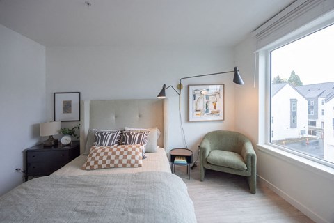 a bedroom with a bed and a chair and a window