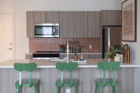 a kitchen with three green stools in front of a counter