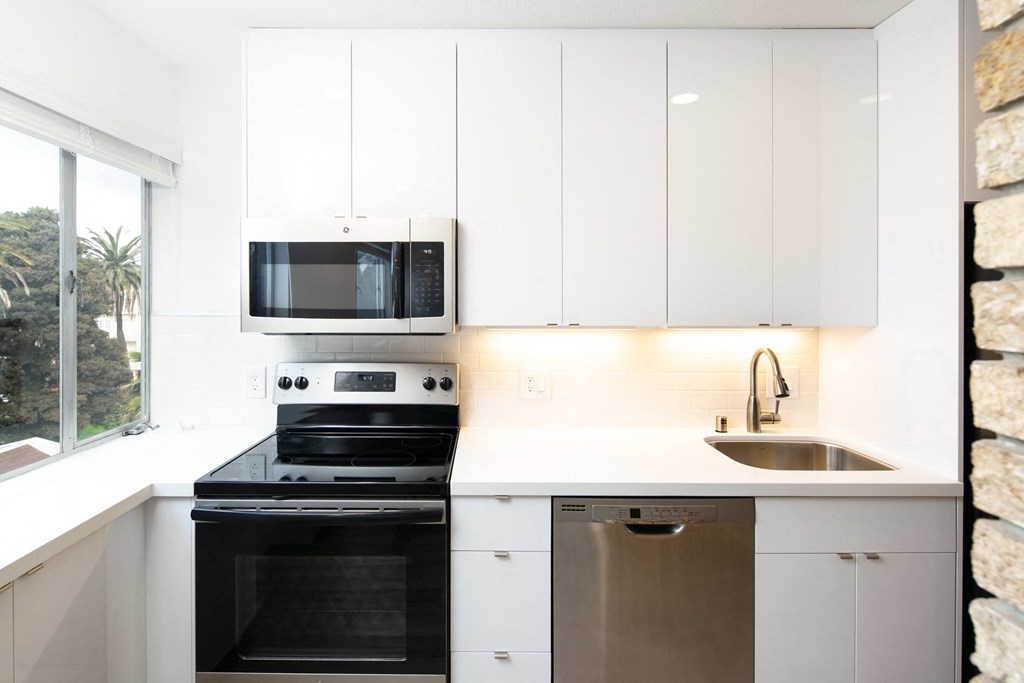 a kitchen with white cabinets and black appliances
