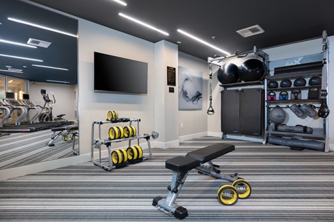 a spacious fitness center with a large tv and weights on the wall