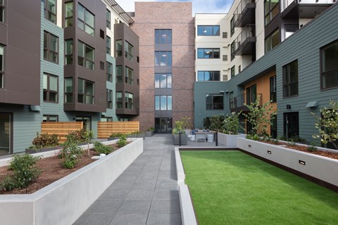 an image of an apartment complex with green grass and a patio