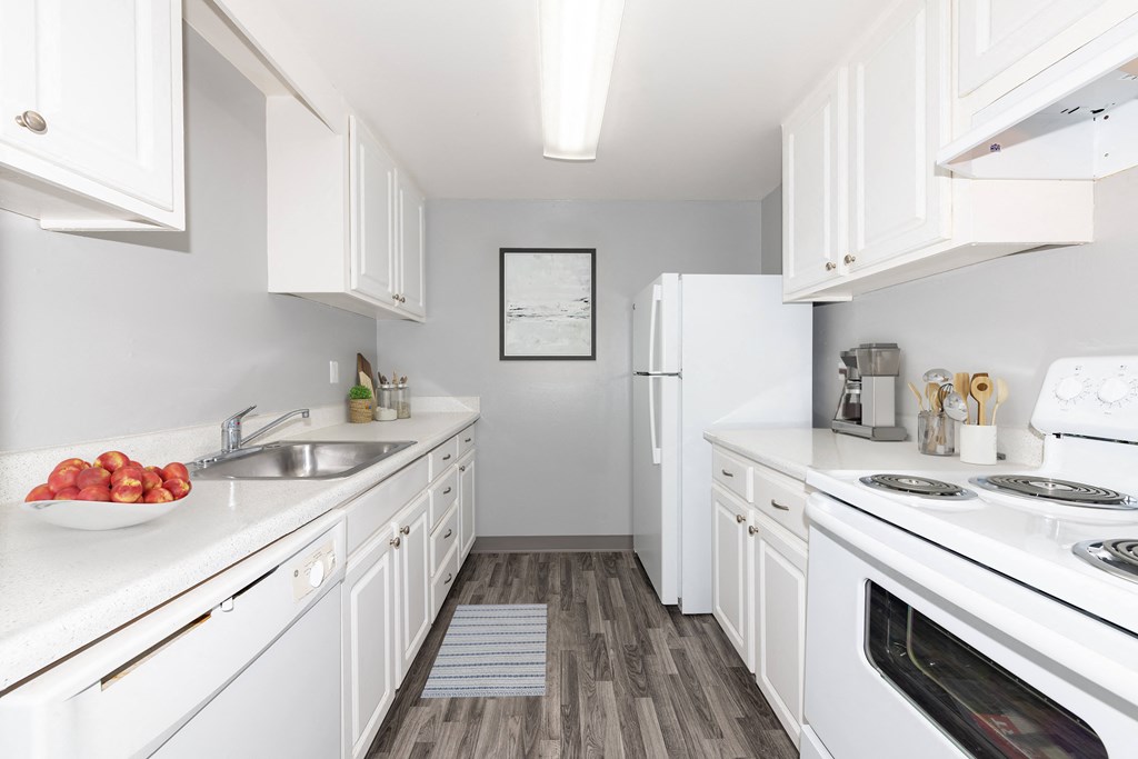 a kitchen with white cabinets and a bowl of fruit on the counter