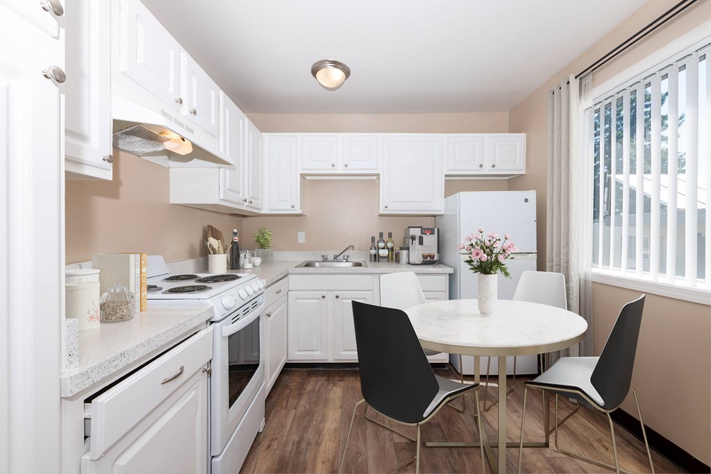 a kitchen with white cabinets and a white table and chairs