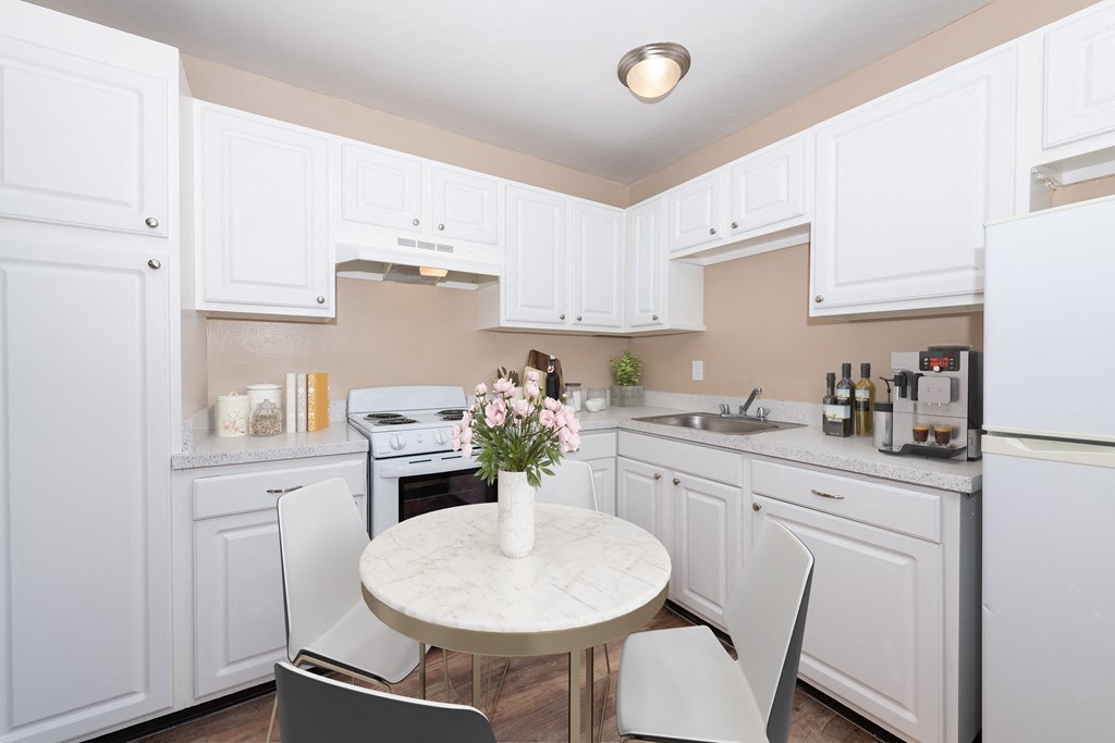 a kitchen with white cabinets and a white marble table with four white chairs