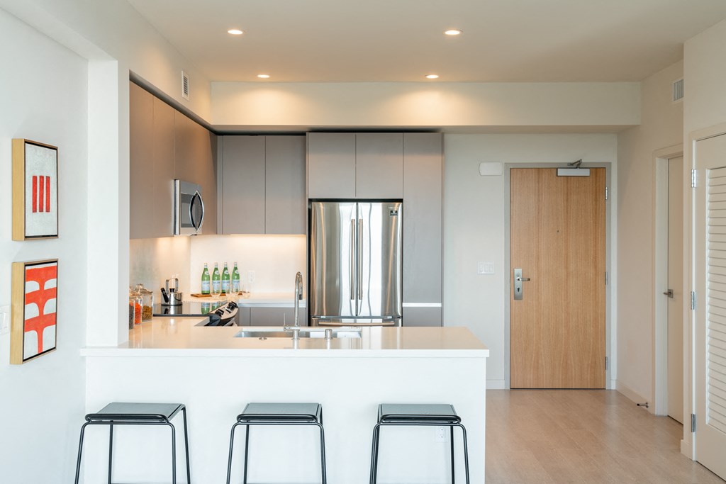 a kitchen with a white counter and three stools
