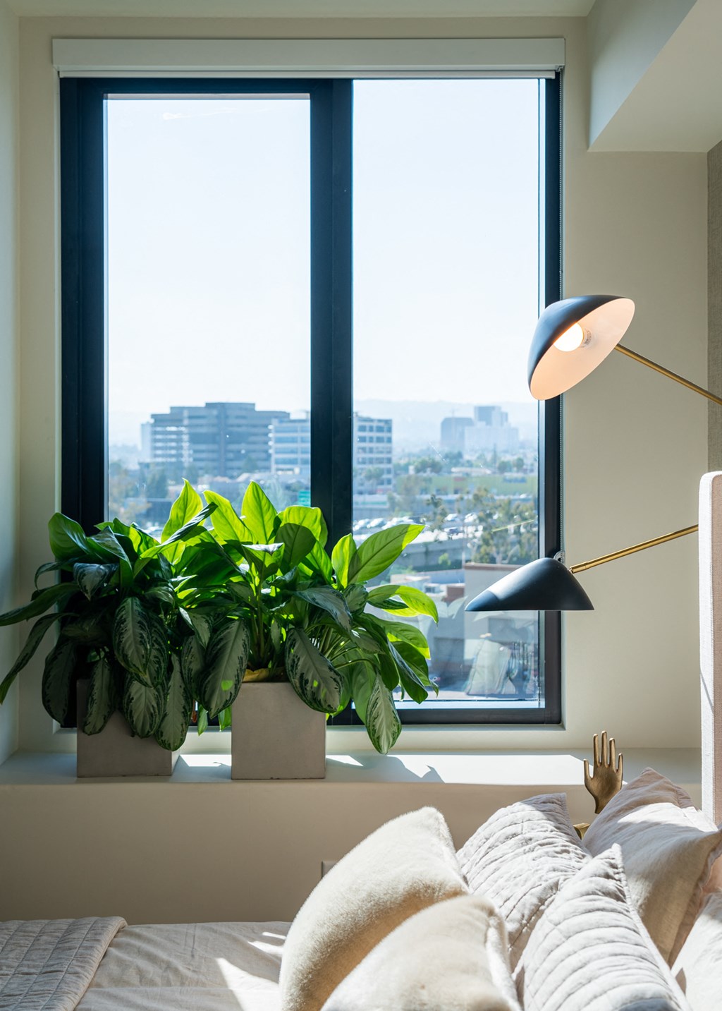 a bedroom with a large window and several potted plants