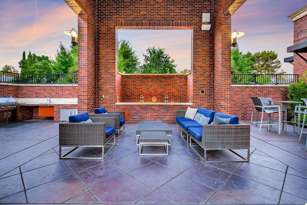 a patio with furniture and a brick fireplace