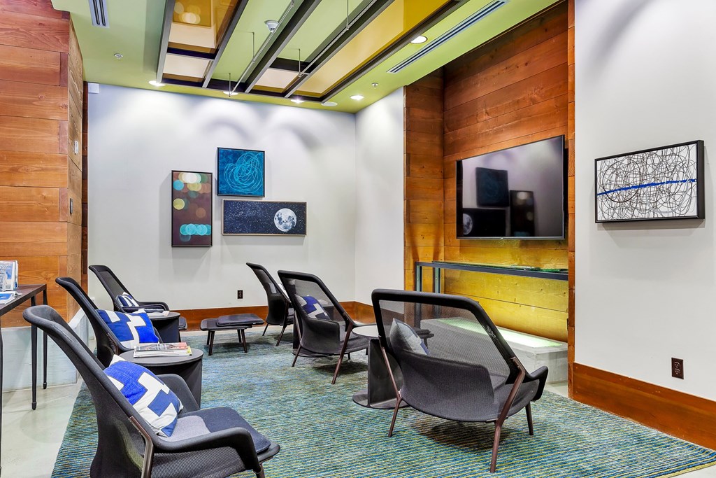 a lounge area with chairs and a television in a room