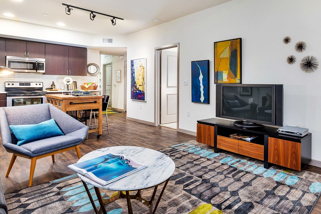 a living room with a tv and a kitchen in the background