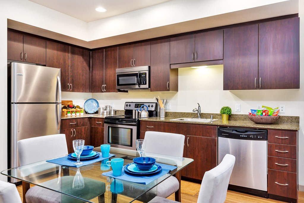a modern kitchen with stainless steel appliances and a glass table