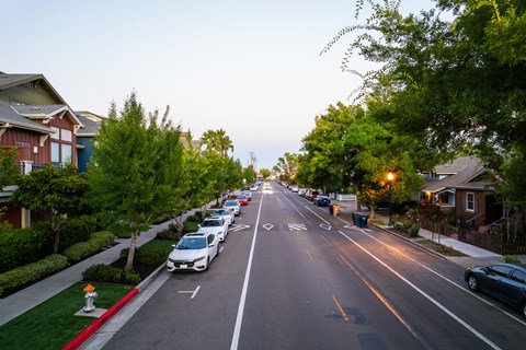 A street with cars parked on the side and houses on both sides.