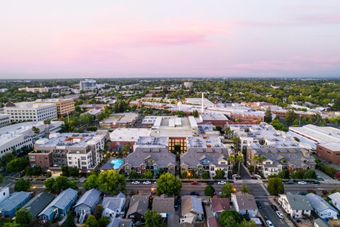 A cityscape with buildings and roads under a pink and blue sky.