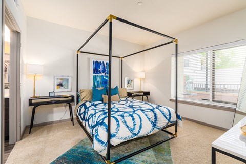 A bedroom with a four-poster bed and a desk.