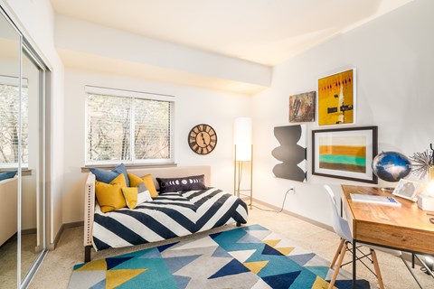 A bedroom with a bed, desk, and chair.