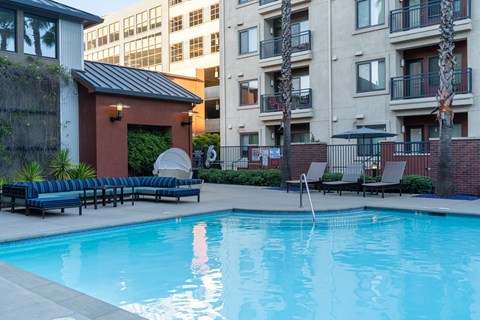A pool with a bench and a building in the background.