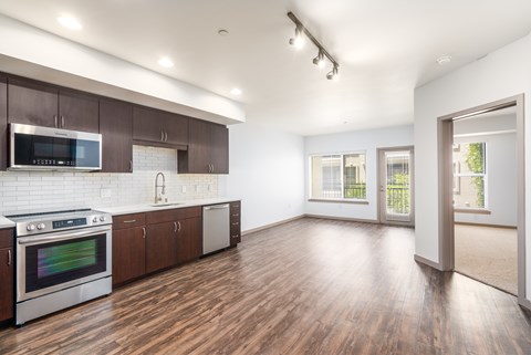 A kitchen with wooden floors and a white tiled backsplash.