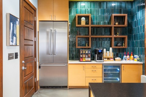 A kitchen with a refrigerator, wooden shelves, and a black countertop.
