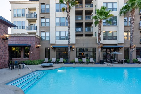 A large swimming pool in front of a multi-story apartment building.