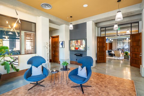 A living room with two blue chairs and a table in the middle.