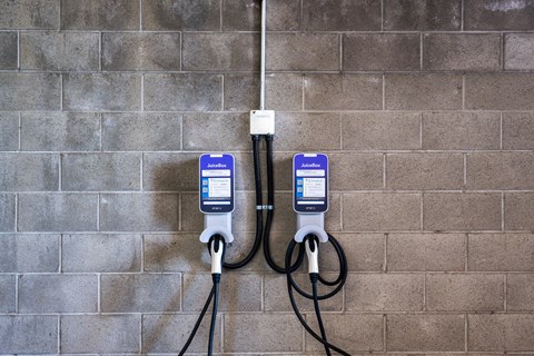 Two electric vehicle charging stations are plugged into a wall.
