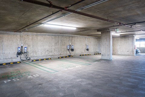 A parking garage with concrete walls and floors, and a few cars parked inside.