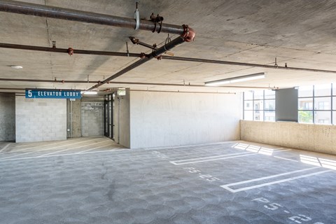The image shows an empty parking garage with a sign that reads "5 Elevator Lobby".