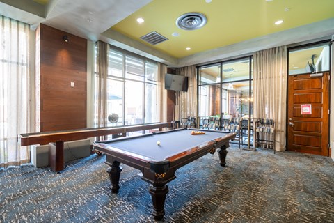 A pool table in a room with a fan and curtains.
