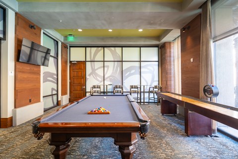 A pool table is in the middle of a room with a TV and a window.