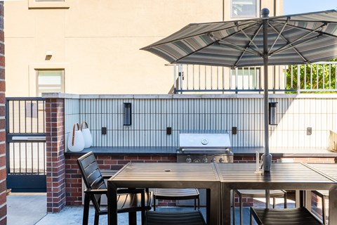 A patio with a table, chairs and an umbrella.