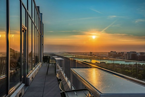 A sunset view from a high-rise building with a pool and chairs.
