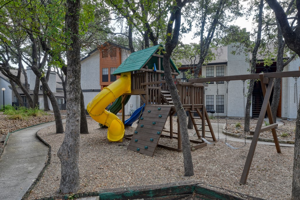 a playground with a large yellow slide and a wooden climbing structure