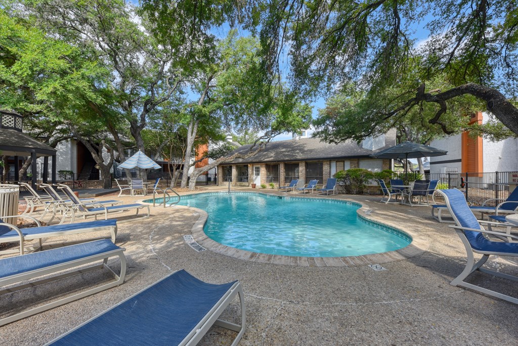 a resort style pool with lounge chairs and umbrellas