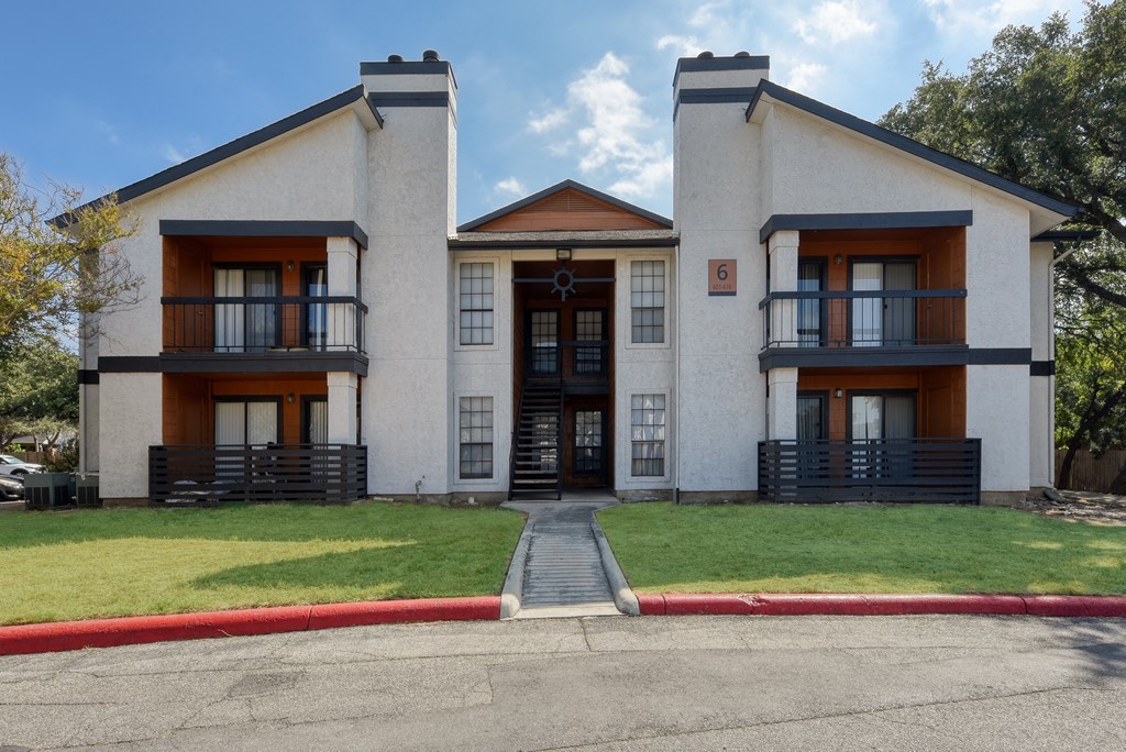 a large white building with brown accents and a sidewalk in front of it