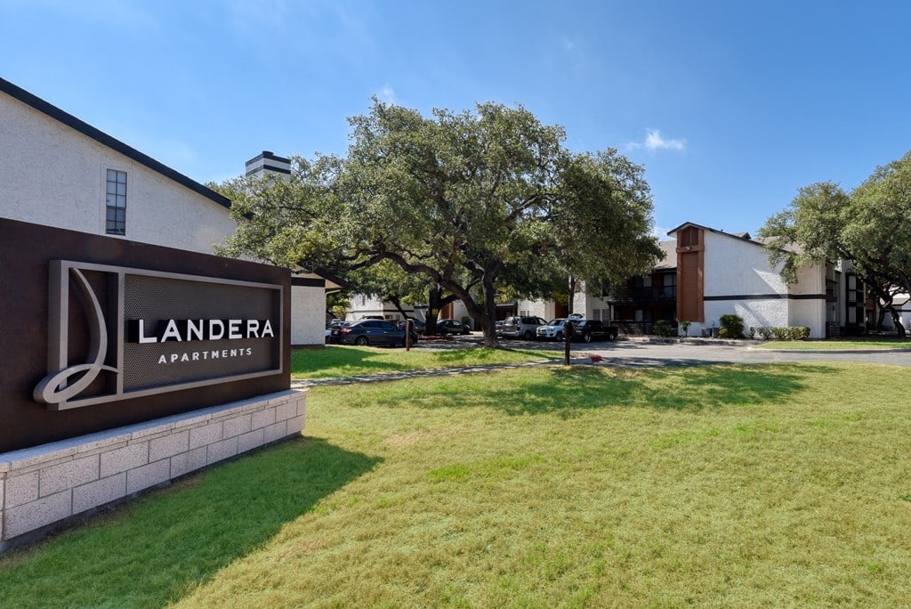 a grassy area in front of a building with a sign that says landera apartments